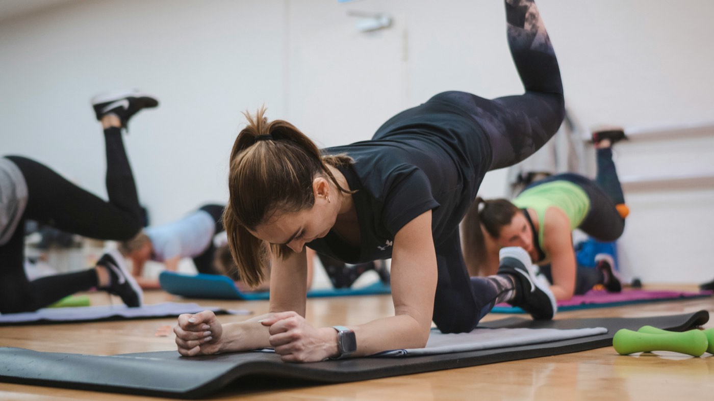 Cours collectif au tapis, travail d'équilibre en appui sur les avant-bras