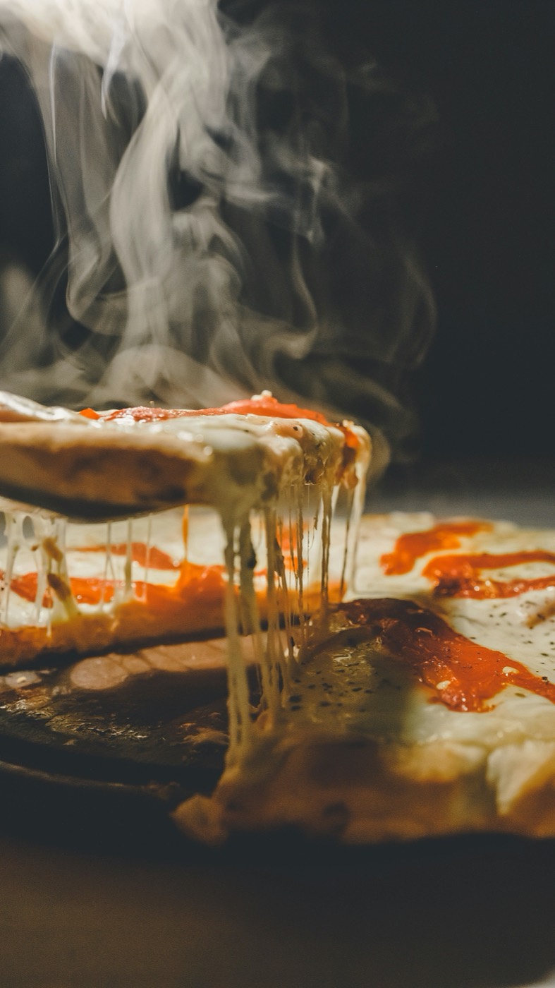 Part de pizza aux quatre fromages, fumante, qui file à la sortie du four